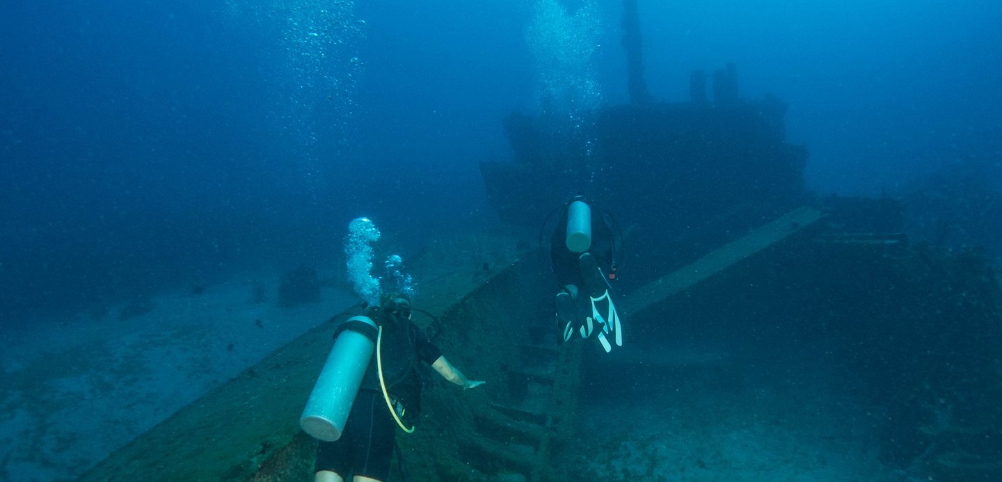 people diving in ship wreck