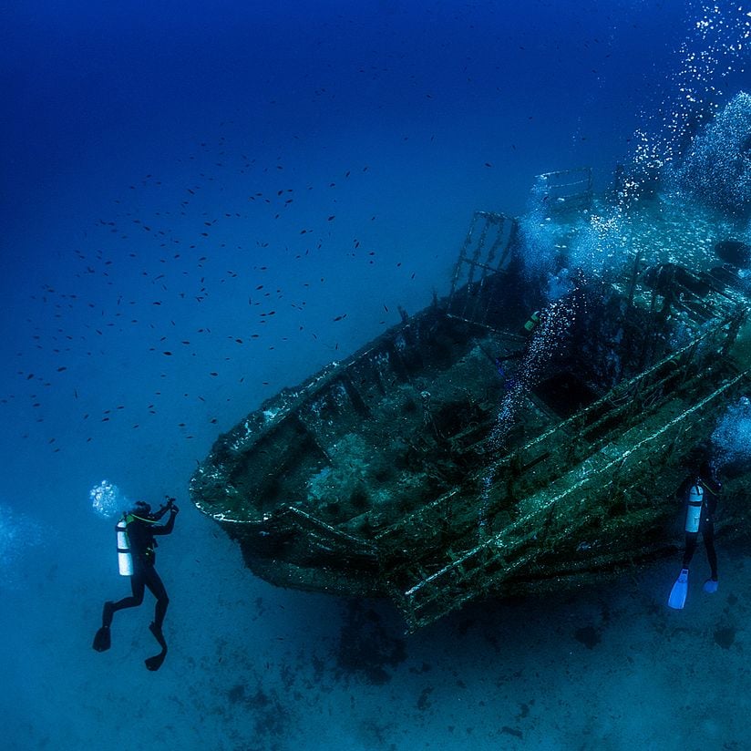 divers next to a ship wreck